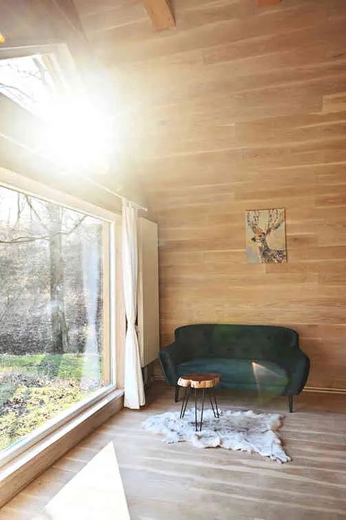 Obývací pokoj chaty Roklinky se zelenou pohovkou a velkým oknem s krásným výhledem